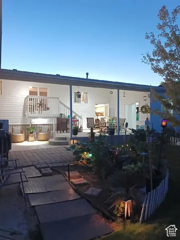 Expansive covered patio with recessed lighting, a multi-level deck featuring white railings, and a paver patio with integrated garden beds