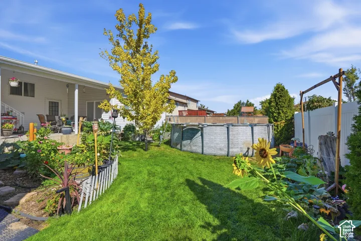 Expansive backyard featuring a manicured lawn, a large above-ground pool, and a white privacy fence