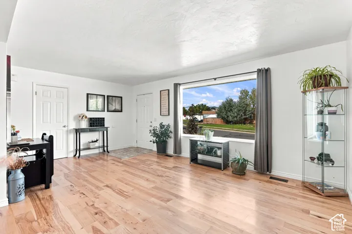 Expansive living area with wood-finish flooring, a large picture window, and white interior doors
