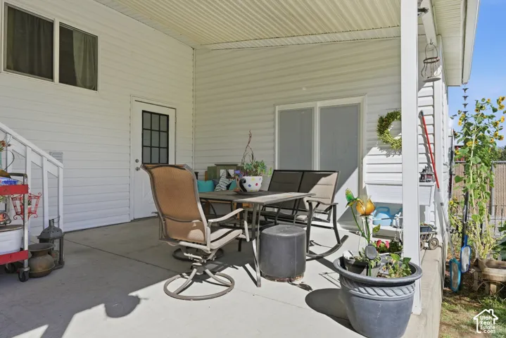 Covered patio with a concrete surface, white vinyl siding, and a white framed door with divided lites