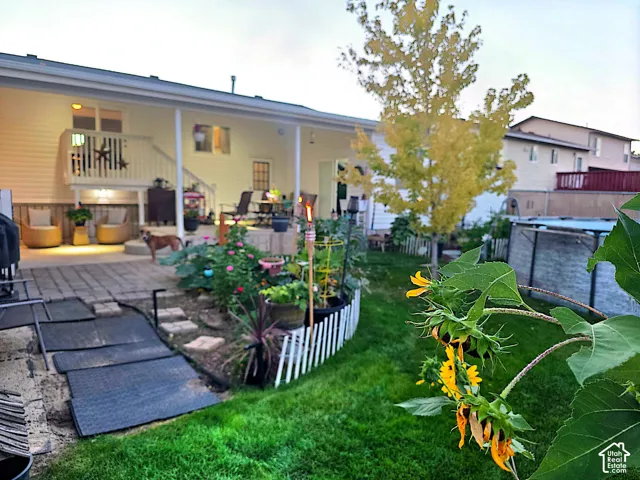Expansive backyard featuring a manicured lawn, established garden beds, and a white picket fence