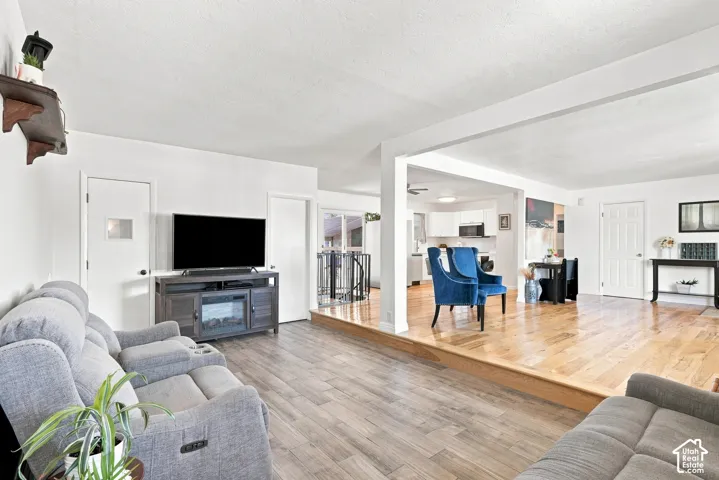 Expansive living area featuring wood-finish flooring, a built-in media console, and an open concept layout with an elevated wood-finish floor section