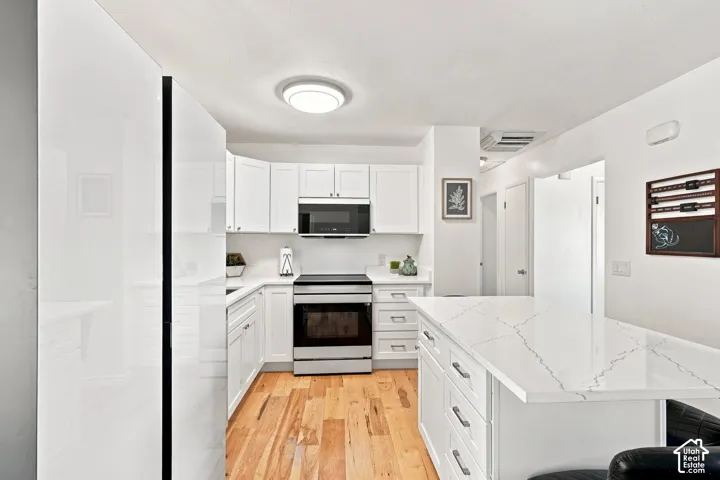 Kitchen featuring a center island with a quartz countertop, wood-finish flooring, white cabinetry, and stainless steel appliances