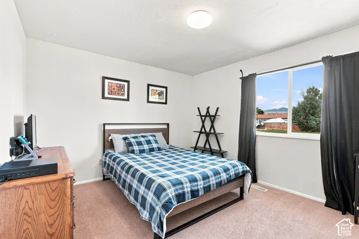 Carpeted room with white walls, a large window with black curtains, and a flush mount ceiling light