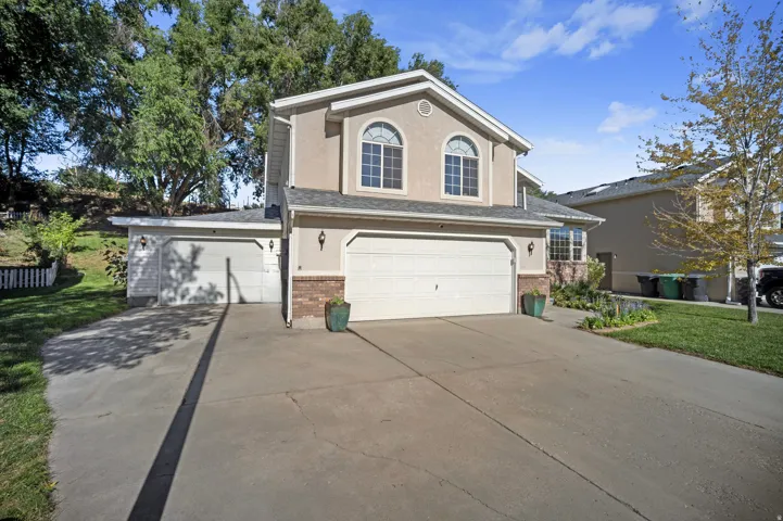 Stucco exterior featuring arched windows, a two-car garage, an additional one-car garage, and a concrete driveway