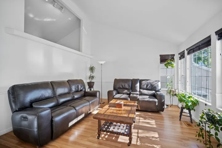 Vaulted ceilings, wood-finish flooring, and natural light from multiple windows