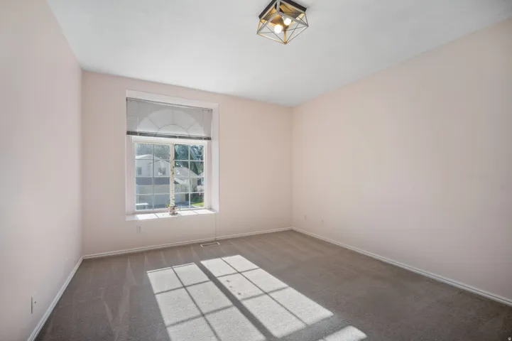 Arched window with gridded panes, flush-mount ceiling fixture, and neutral-toned wall paint