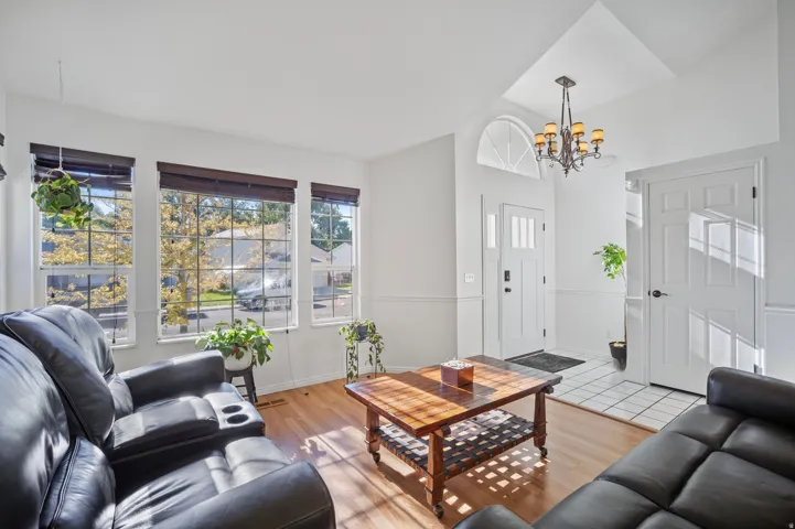 Hardwood-style flooring, transom window, chandelier, white trim, and multiple windows