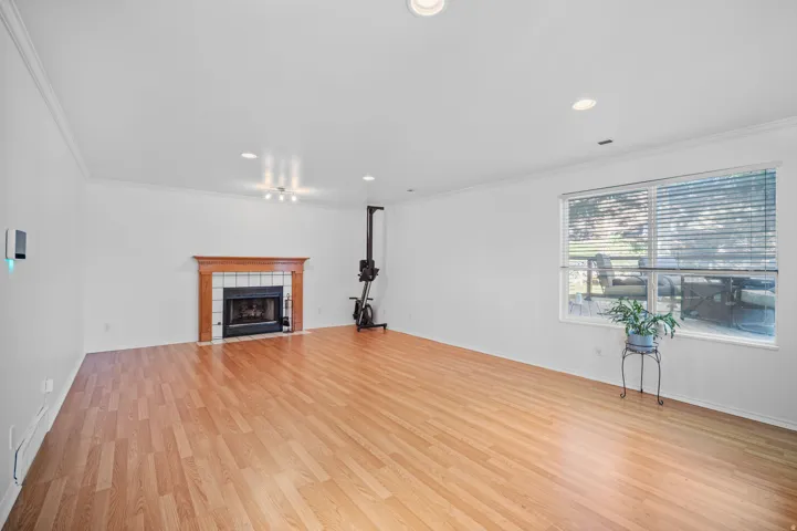 Wood-finish flooring throughout, white walls, and a fireplace with a wood mantle and tile surround