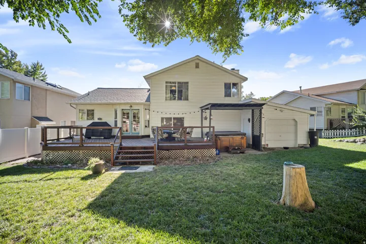 Expansive lawn with a multi-level wood deck, white privacy fence, and a detached shed structure