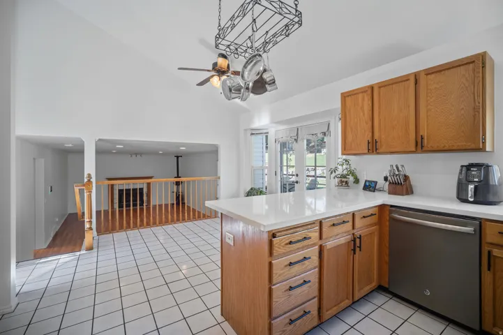 Kitchen featuring white tile flooring, wood cabinetry with black hardware, white countertops, and a stainless steel dishwasher