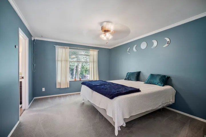 Recessed window with natural light, ceiling fan fixture, crown molding, light-colored carpet, and wall-mounted light fixture