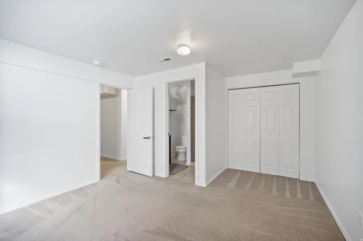 Neutral tone carpet flooring, white walls, and a ceiling-mounted light fixture