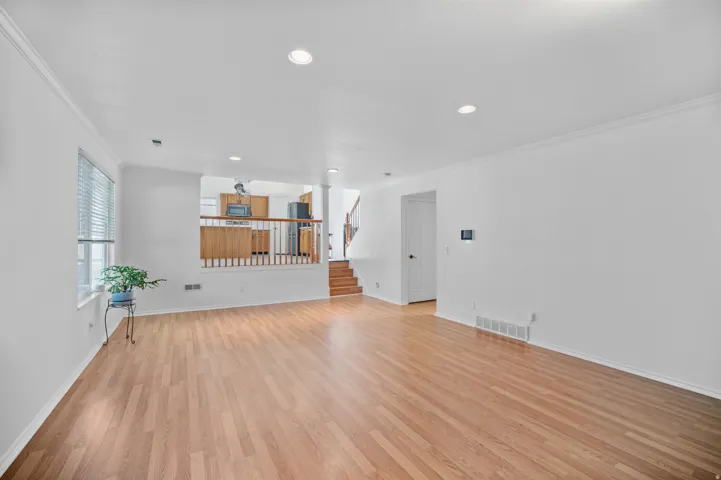 Wood-finish flooring throughout, recessed lighting, and a half-wall partition with wood balusters