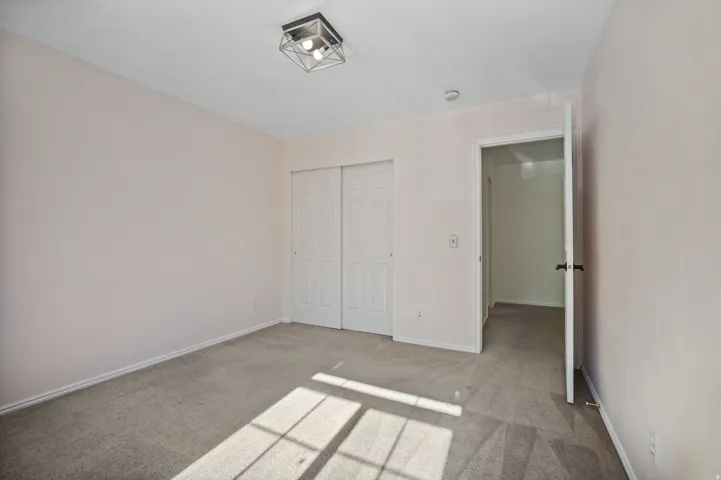 Neutral wall paint, gray carpet flooring, flush mount light fixture, sliding closet doors, and interior doorway
