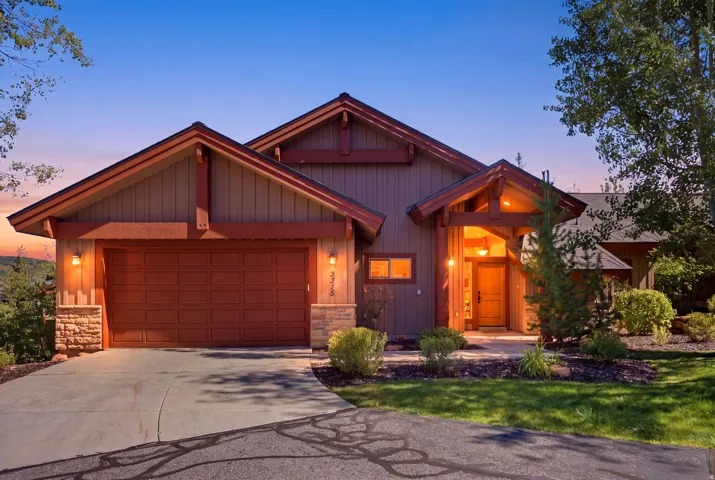 Craftsman-style exterior with wood siding, stone accents, a covered entry, and an attached garage