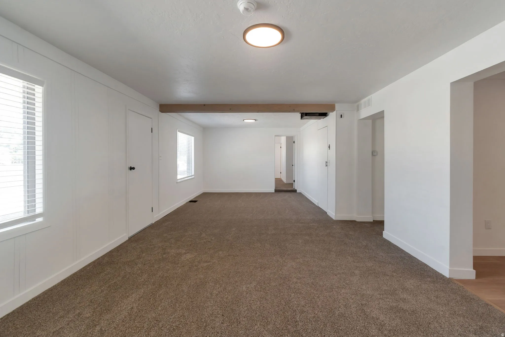 Bright interior featuring recessed windows, white paneled walls, and a wood-finish ceiling beam