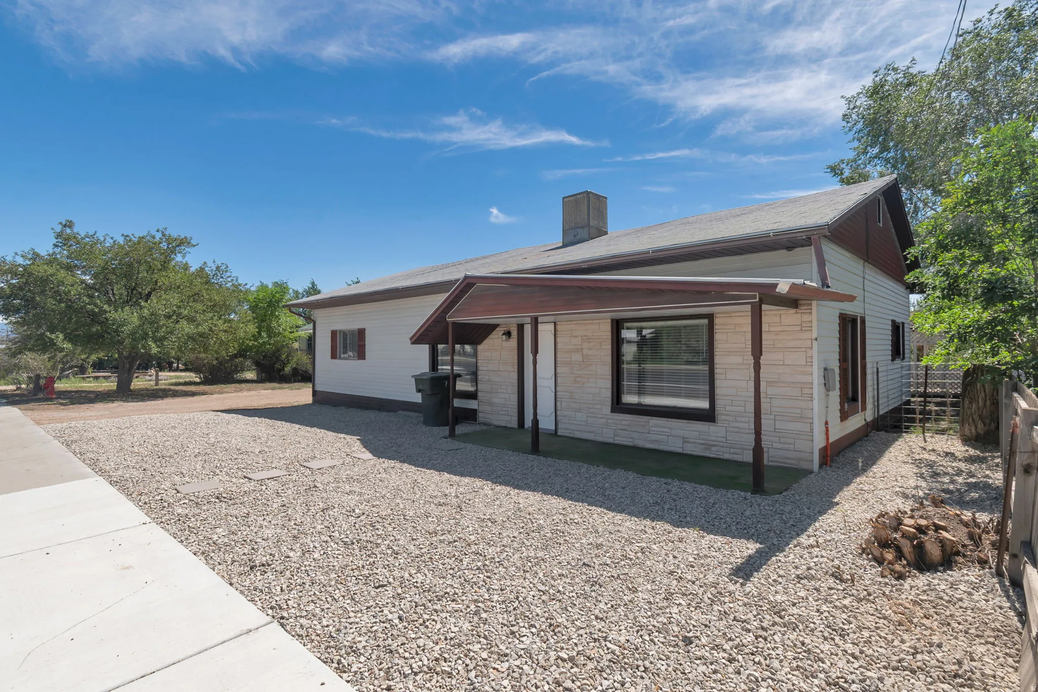 Stone veneer facade with a covered entry, gabled roofline, and gravel landscaping