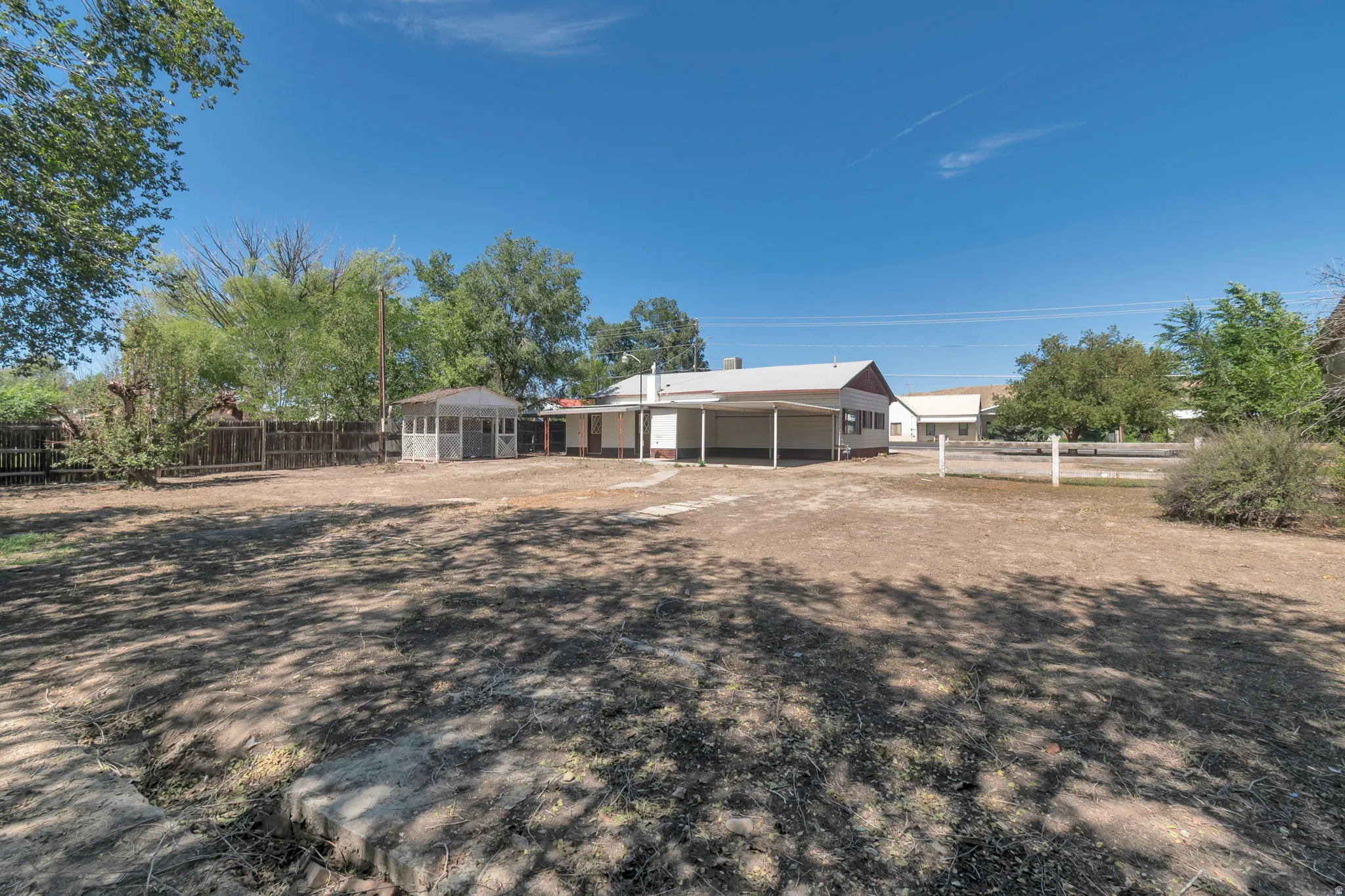 Large outdoor area with a covered patio, a detached gazebo, and a perimeter fence
