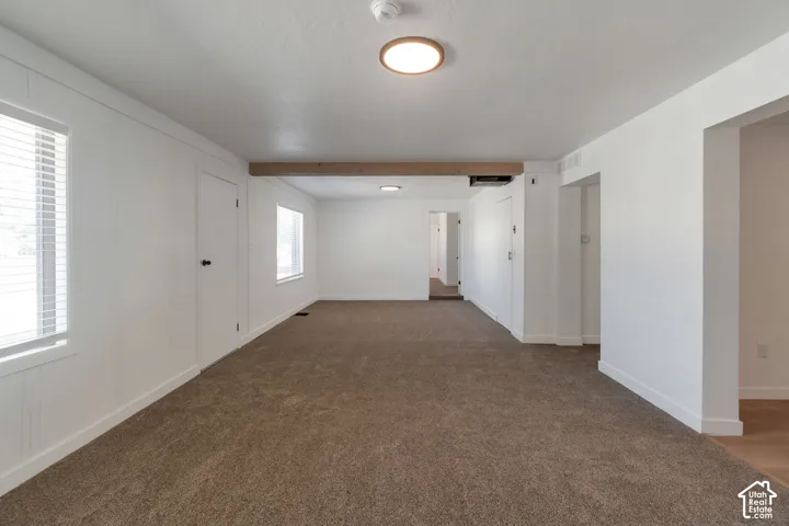 Bright interior featuring recessed windows, white paneled walls, and a wood-finish ceiling beam