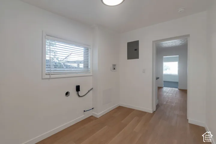 Light wood-finish flooring with white baseboards, window with blinds, and ceiling-mounted lighting fixture