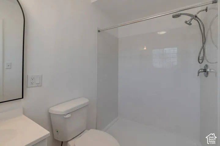 White vanity with an integrated sink, black-framed arched mirror, and a walk-in shower with white subway tile