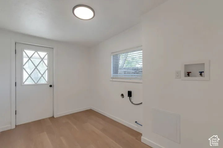 Laundry area featuring wood-finish flooring, a contemporary flush-mount ceiling light, a window with blinds, and appliance connections