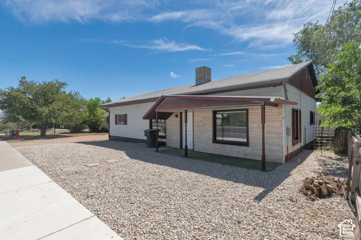 Stone veneer facade with a covered entry, gabled roofline, and gravel landscaping