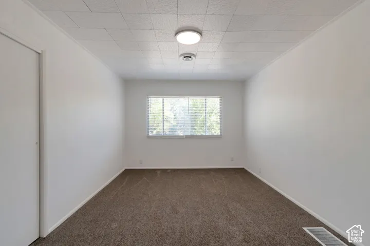 Neutral wall finishes, recessed window, wall-to-wall carpeting, acoustic panel ceiling, and flush mount lighting