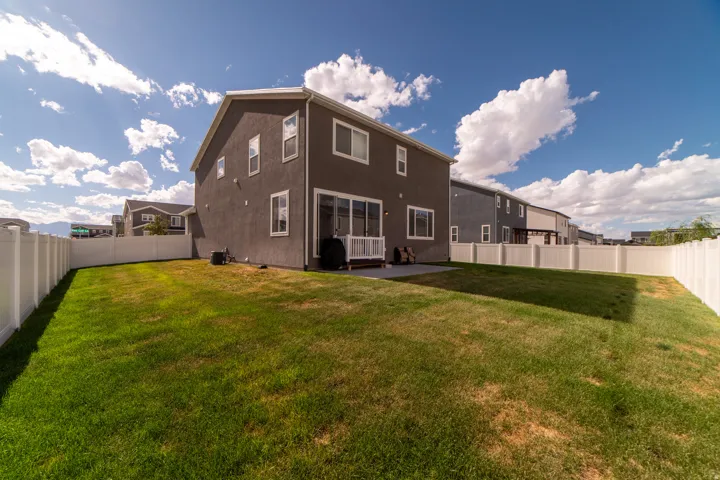 Expansive backyard with a manicured lawn, full vinyl privacy fencing, and a concrete patio
