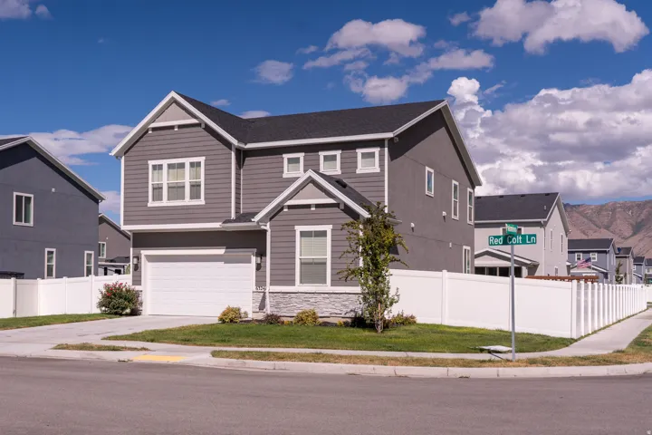 Two-story residence with a dark shingle roof, gray siding, and white trim accents