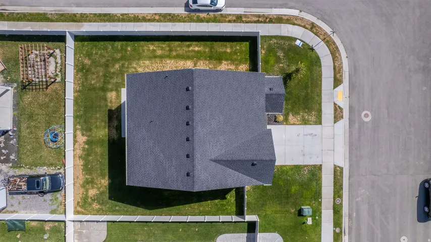Asphalt shingle roof, concrete driveway, concrete sidewalk, perimeter fencing, and a corner lot