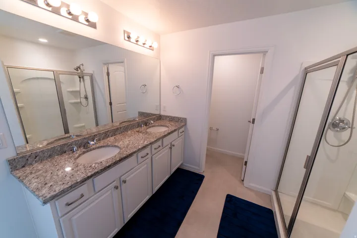 Dual vanity with granite countertop, white cabinetry, and undermount sinks