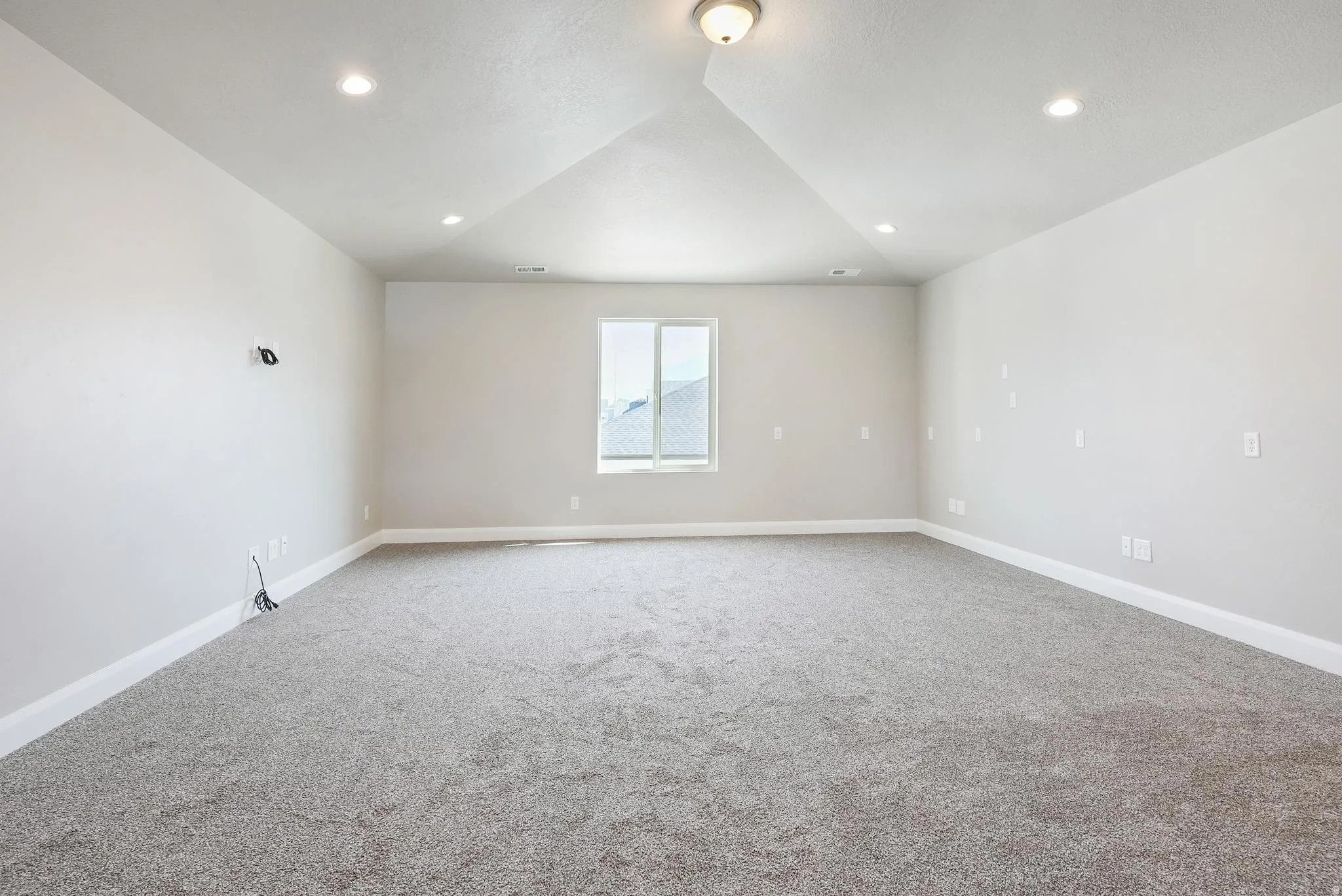 Spacious room with gray carpeting, white walls, recessed lighting, and a tray ceiling