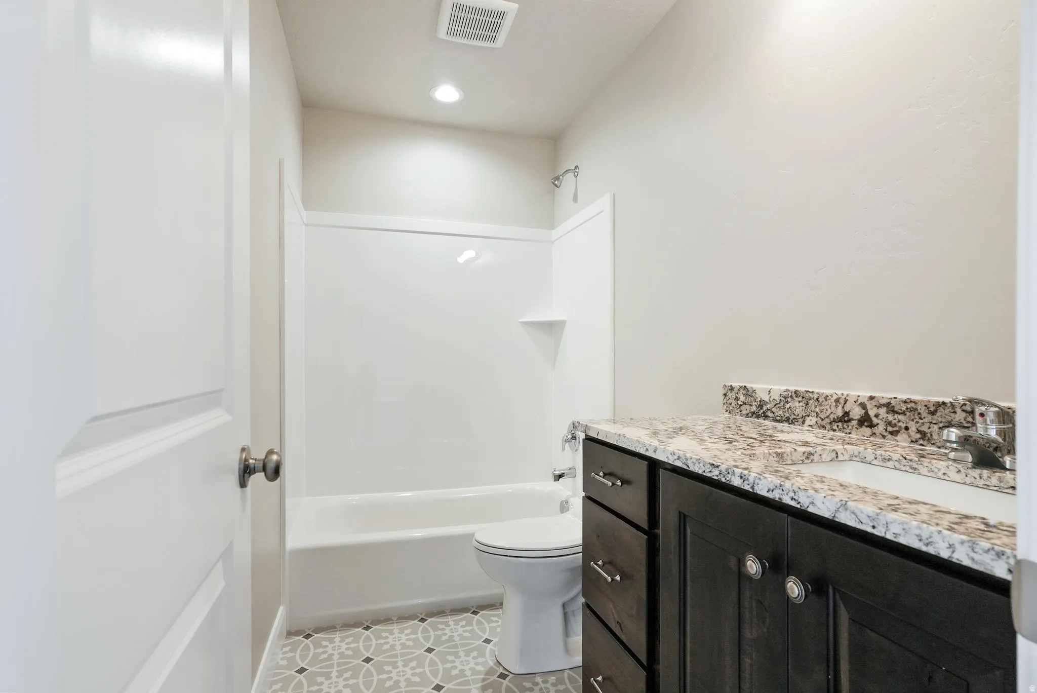 Single vanity with a light granite countertop, dark wood-finish cabinetry, and an integrated white sink