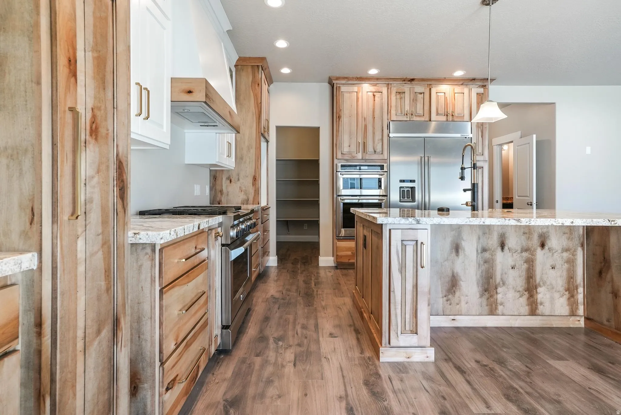Kitchen featuring a large island, wood-finish flooring, stainless steel appliances, recessed lighting, and a pantry with built-in shelving