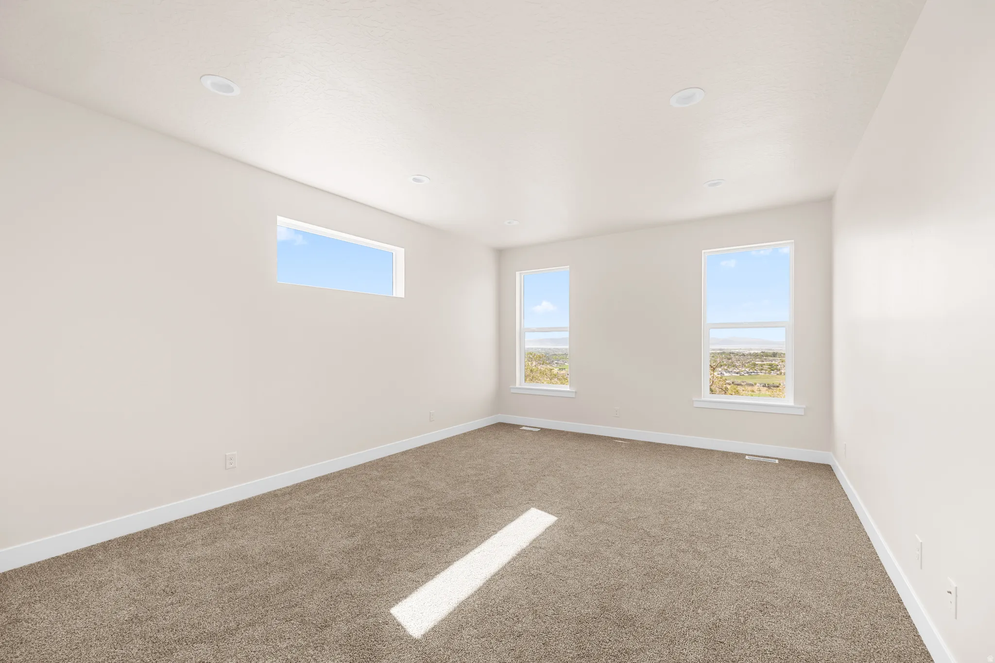 Plush carpeted flooring, recessed lighting, and multiple windows providing ample ambient light