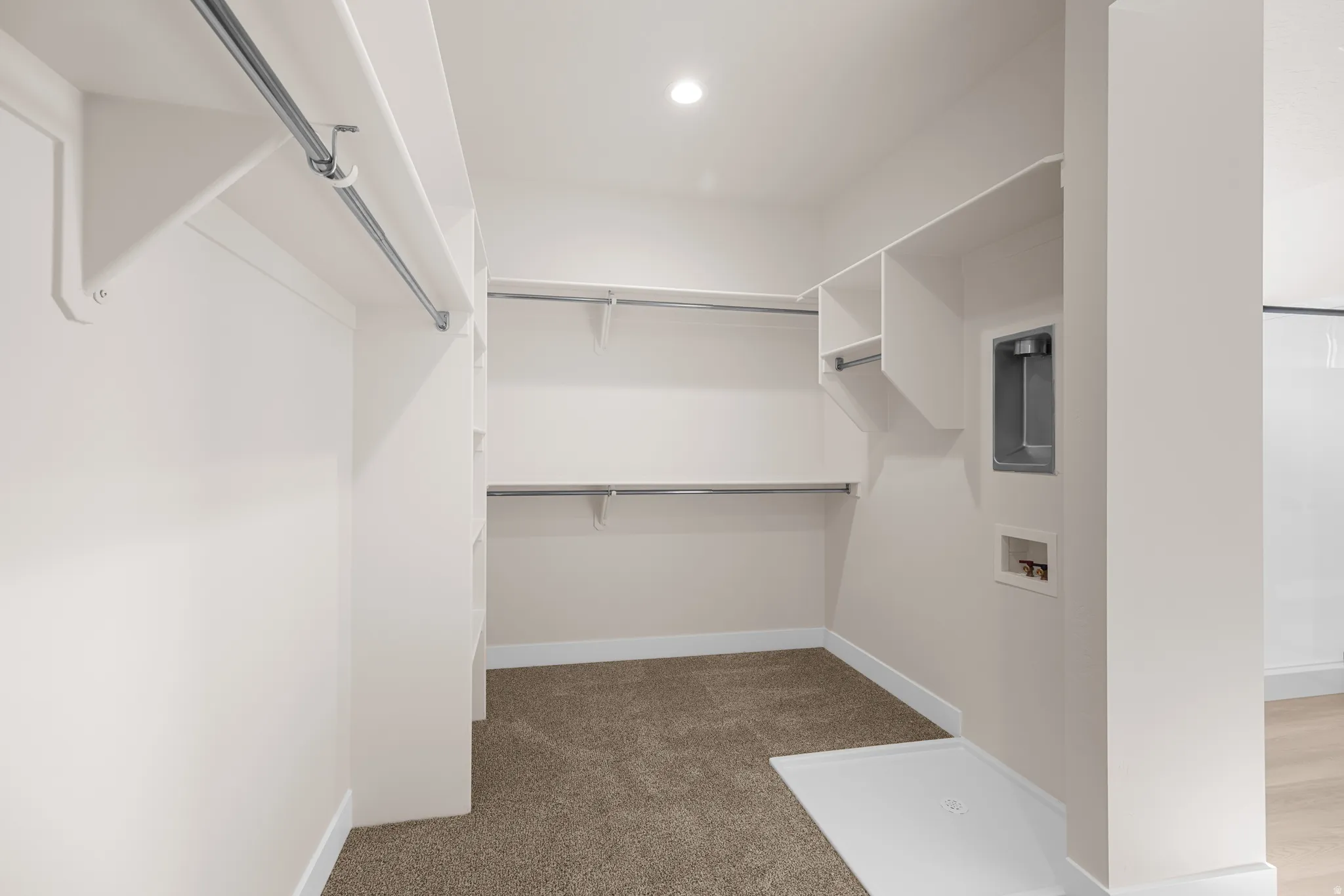 Walk-in closet featuring extensive shelving, hanging rods, carpet flooring, recessed lighting, and laundry hookups
