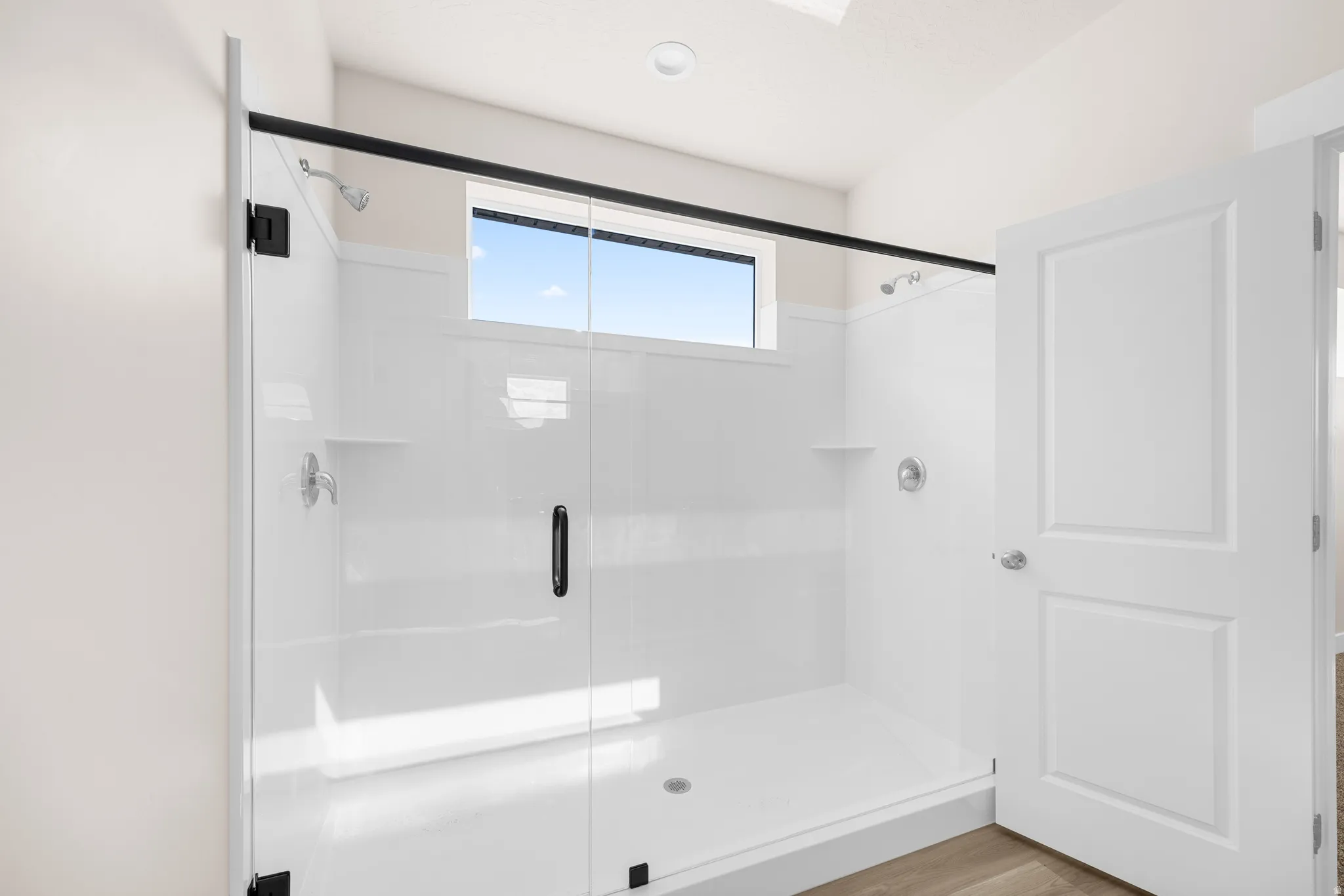 Walk-in shower with clear glass enclosure and black hardware