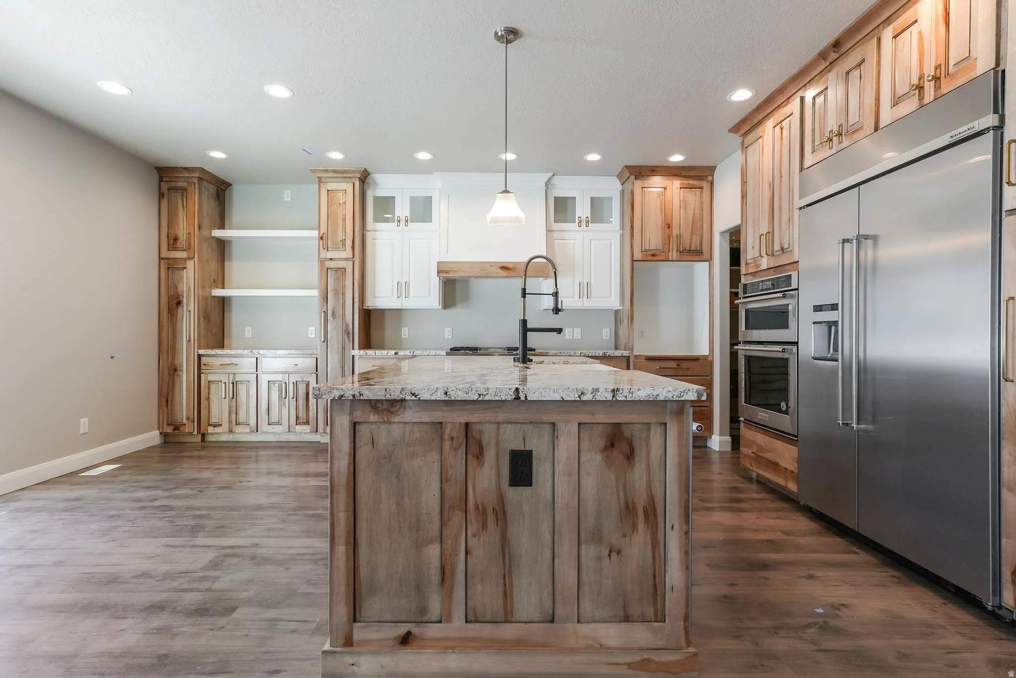 Kitchen featuring a large central island with a stone countertop, built-in stainless steel appliances, wood-finish cabinetry, and recessed lighting