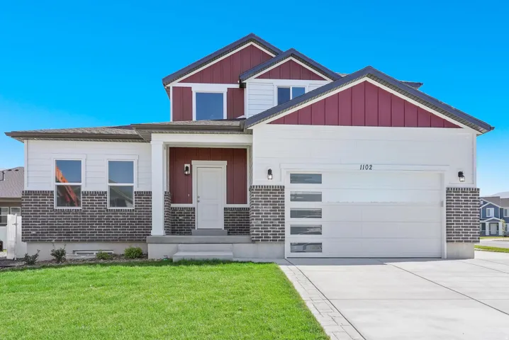 Contemporary exterior with a white and burgundy facade, brick accents, concrete driveway, and attached garage with frosted windows