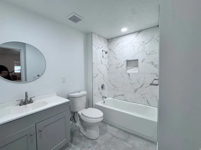 White tiled bath and shower with recessed shelf