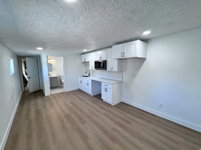 Wood-finish flooring throughout, white cabinetry with modern hardware, recessed lighting, and a built-in microwave