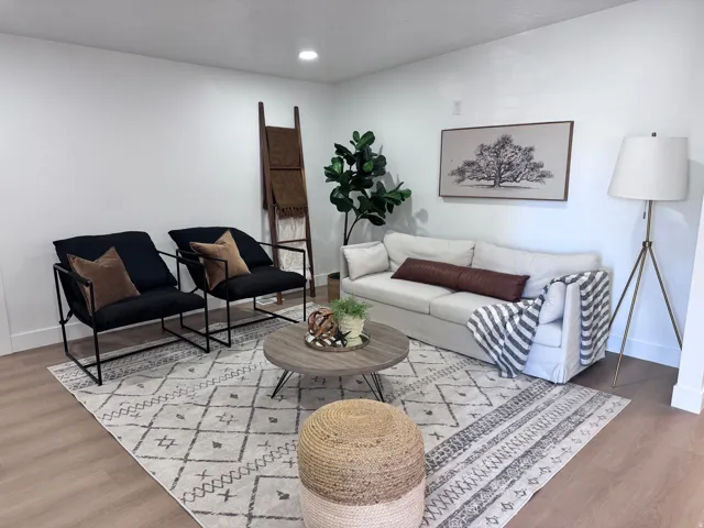 Bright living room featuring hardwood flooring, geometric patterned area rugs, and a round wood-finish cocktail table