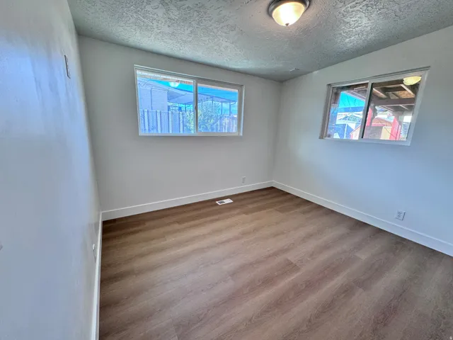 Wood-finish flooring, white wall paint, two windows, ceiling-mounted light fixture, and white trim