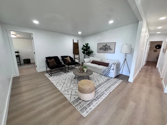 Recessed ceiling lighting, wood-finish flooring, white wall finishes, white trim, and a wide entryway