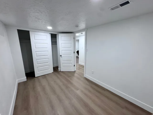 Wood-finish flooring, white paneled doors, built-in closet with sliding doors, recessed lighting, and white baseboards