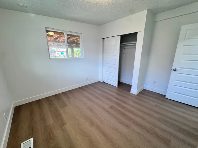 Wood-finish flooring throughout, bright white walls, and a window with white trim