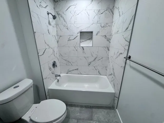 Bathtub with subway tile surround, recessed shelf, and chrome fixtures