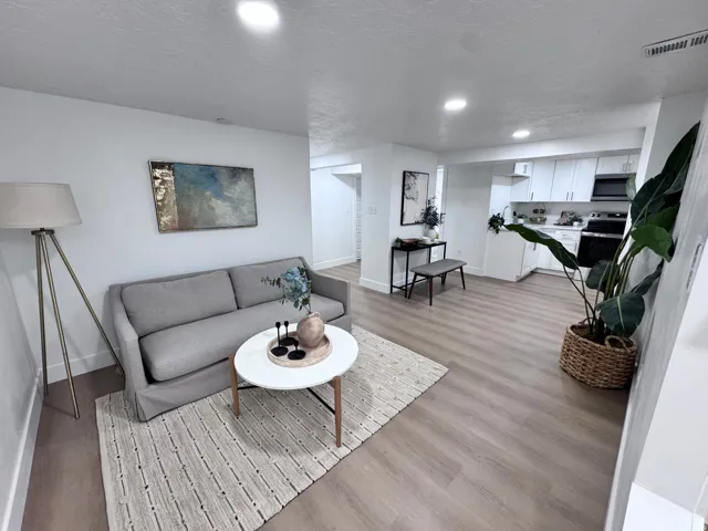 Open-concept living area with wood-finish flooring, recessed lighting, and white cabinetry in the kitchen